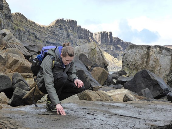 Dr Elsa Panciroli crouching on a large rock