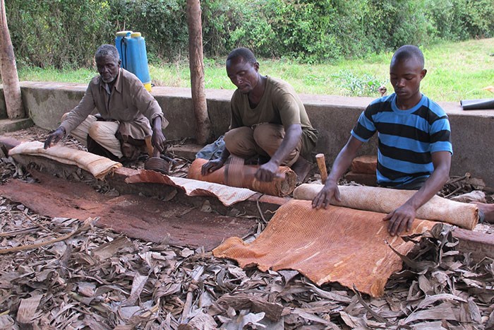 3 men sitting making barkcloth