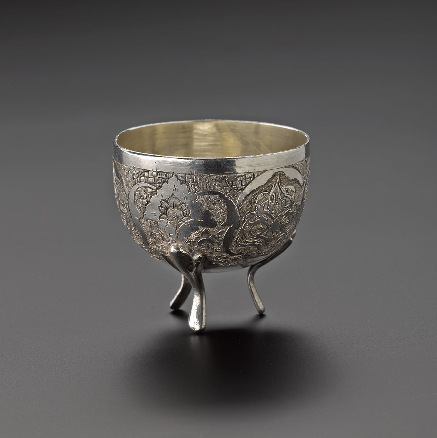 Bowl of silver, with three feet and chased stylized floral decoration around the outside, used as part of a set with a spoon: Iran, probably Isfahan, 1920s-1940s, acc. no V.2015.69.1 