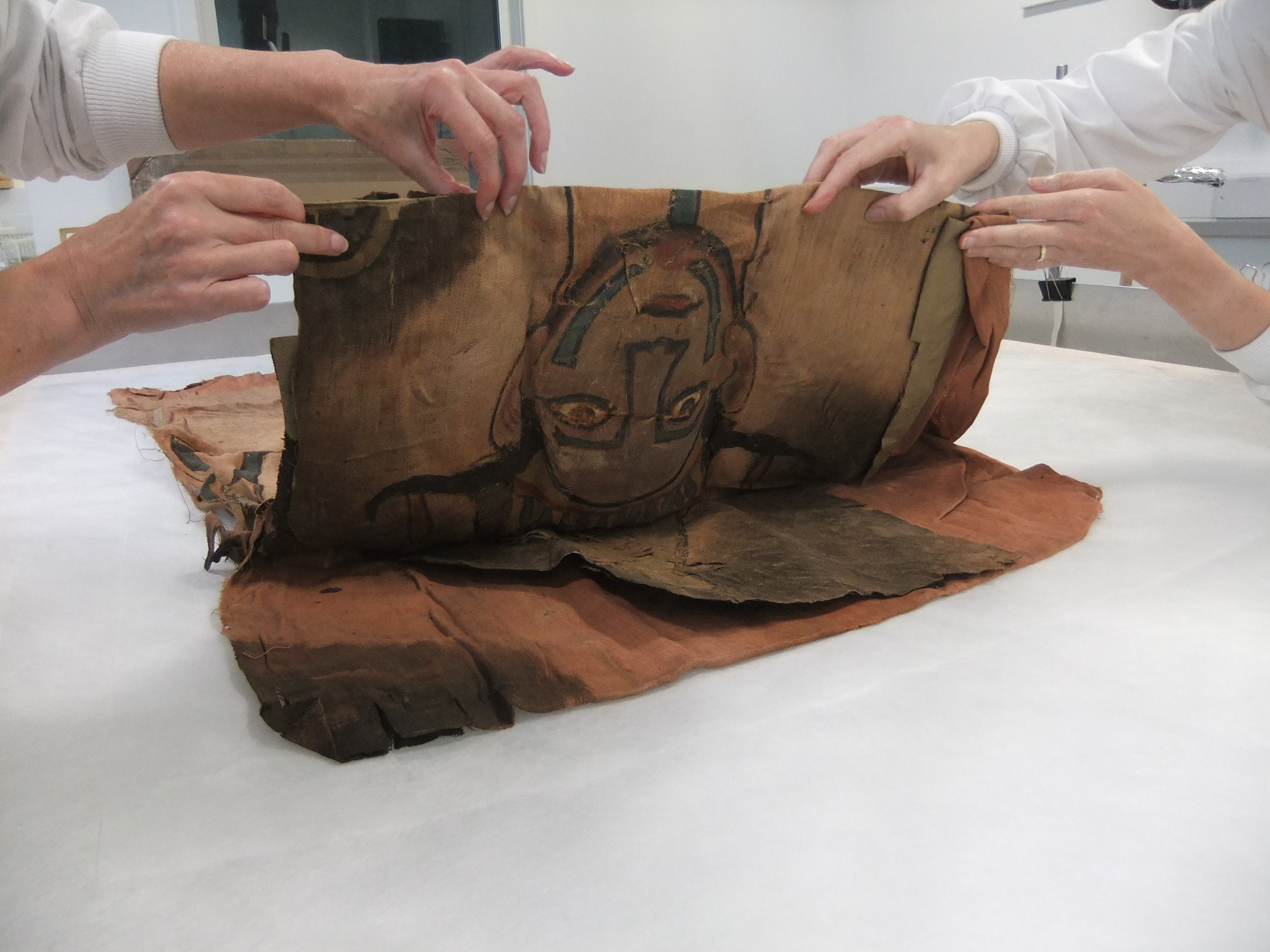The shroud is unfolded by textile conservators at National Museums Scotland.