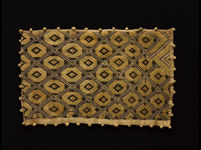 Rectangular raffia cloth, decorated with cut pile lozenge pattern, in three colours on a natural ground, border with small pom-poms at intervals: Africa, Central Africa, Democratic Republic of the Congo, Kasai, early 20th century.