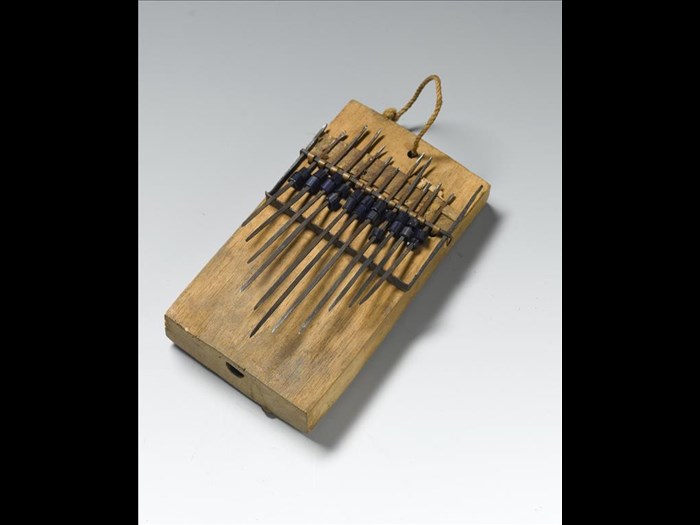 Thumb piano or likimbe, a hollowed wooden box with vibrating iron tongues, decorated with blue glass beads: Africa, Central Africa, Democratic Republic of the Congo, Lokombe, early 20th century.
