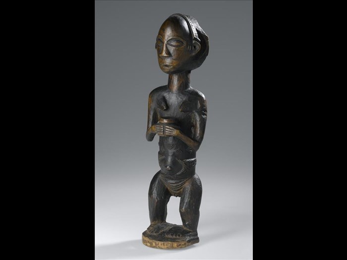 Carved wooden standing female figure  with dressed hair and body scarification, holding a jar with both hands: Africa, Central Africa, Democratic Republic of the Congo, Katanga, late 19th century.