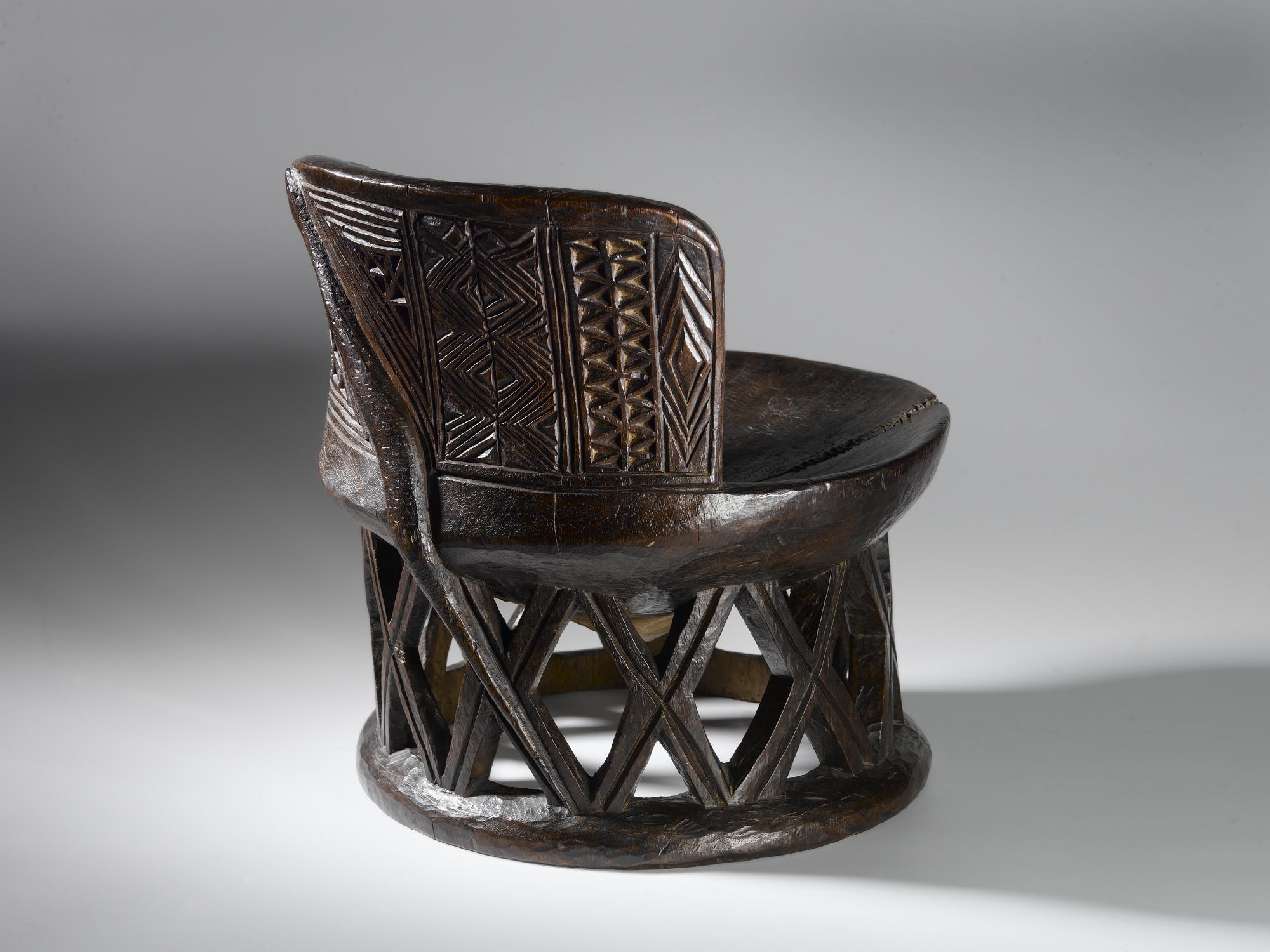 Circular wooden stool with wire repair on seat, curved back and open lattice-work base, carved geometric patterns on seat back and serpent carved on back of stool from top to base: Africa, Central Africa, Democratic Republic of the Congo, Tanganyika Plateau, Bemba people, late 19th century.