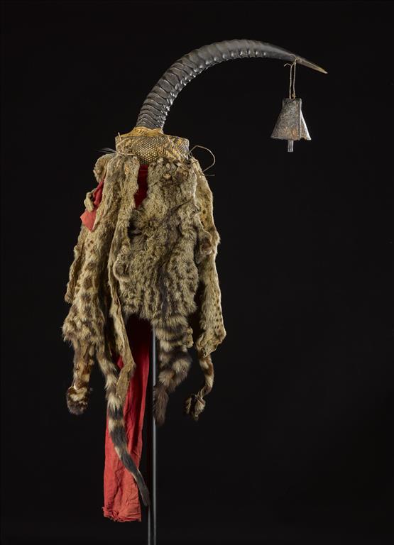 Antelope horn decorated with an iron bell, Palm Civet (Nandinia binotata) skins and a length of red cotton cloth, attached to a woven basket core, known as a lilamfia, used for divination in warfare: Africa, Southern Africa, Zambia, Tanganyika Plateau, Awemba, late 19th century.