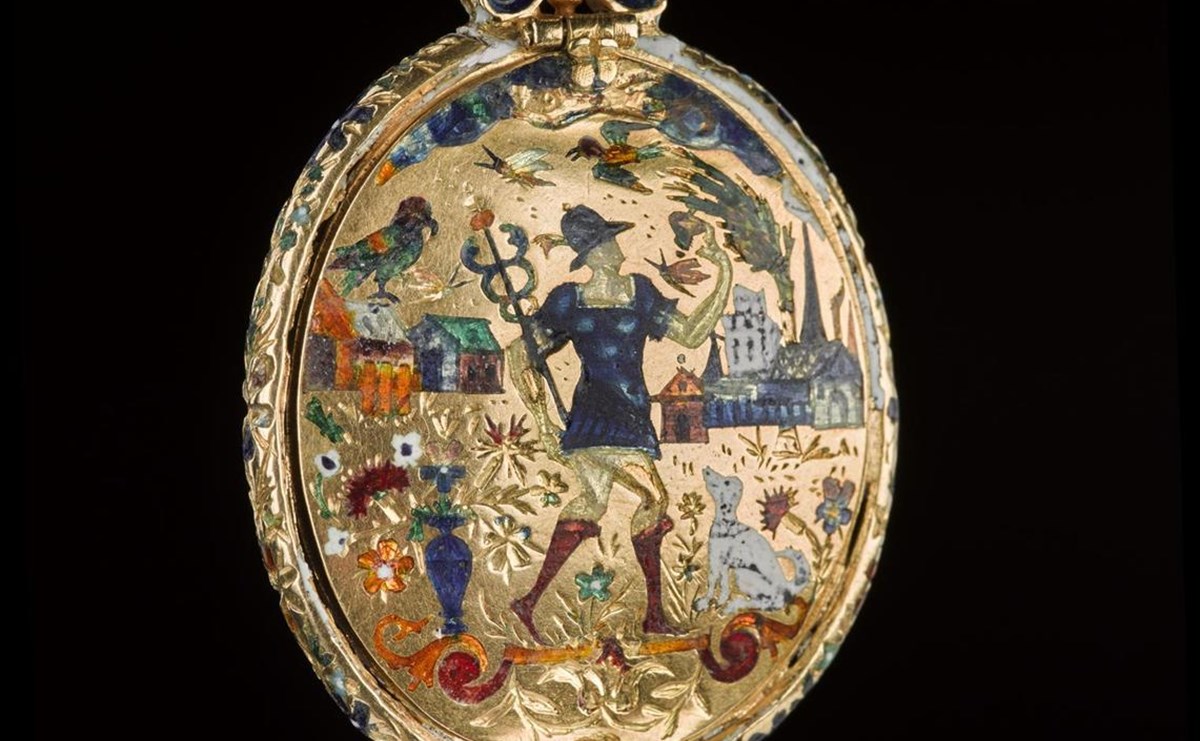 Gold locket with a colourful scene of a person, animals, houses, and plants