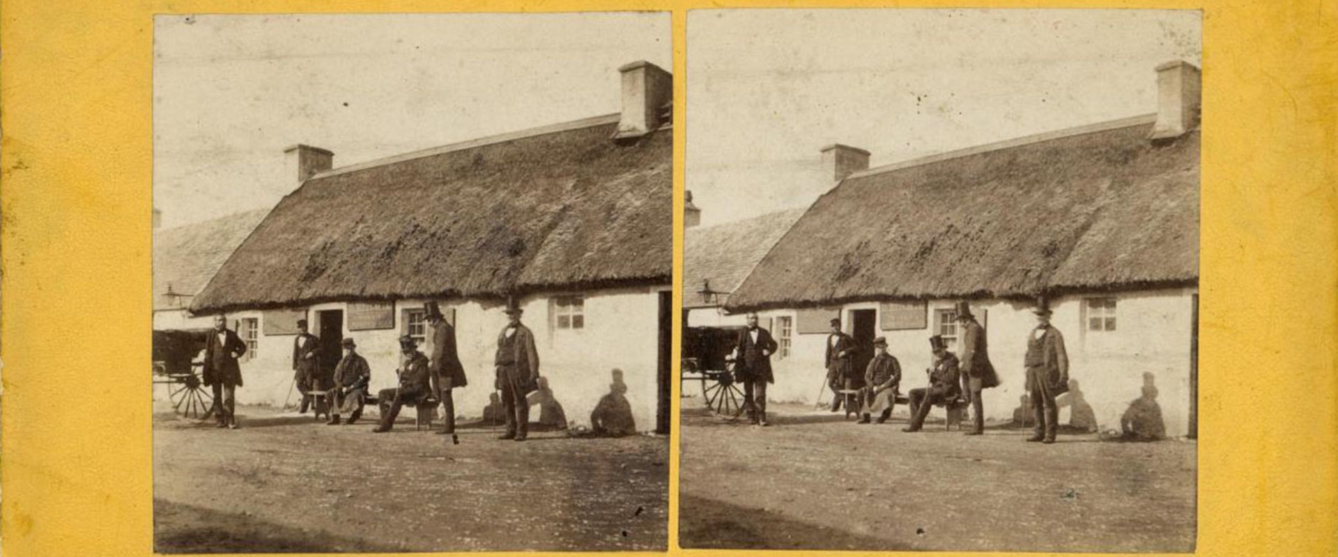 Yellow stereocard with two identical images of people standing in front of a single-storey thatched house.