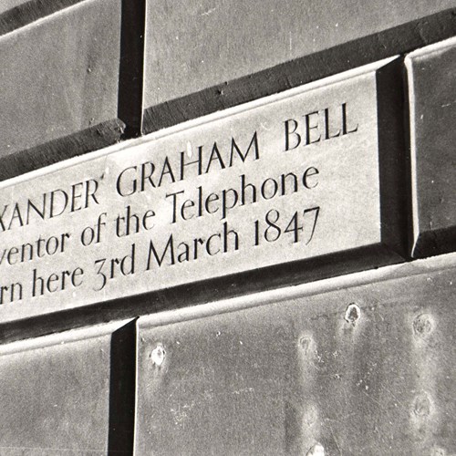 Plaque on a stone wall with deeply cut lines reading 'Alexander Graham Bell Inventor of the telephone Born here 3rd March 1847'.