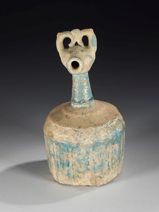 Bottle of ground quartz and clay with a turquoise alkaline glaze, the sides moulded with vertical ribs, and top in form of a stylised ibex head: Persia, Rayy type, late 12th to early 13th century.