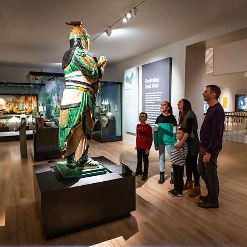 A family looking up at a statue in the Exploring East Asia gallery.