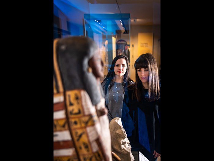 Two visitors examine a sarcophagus in the Ancient Egypt gallery. 