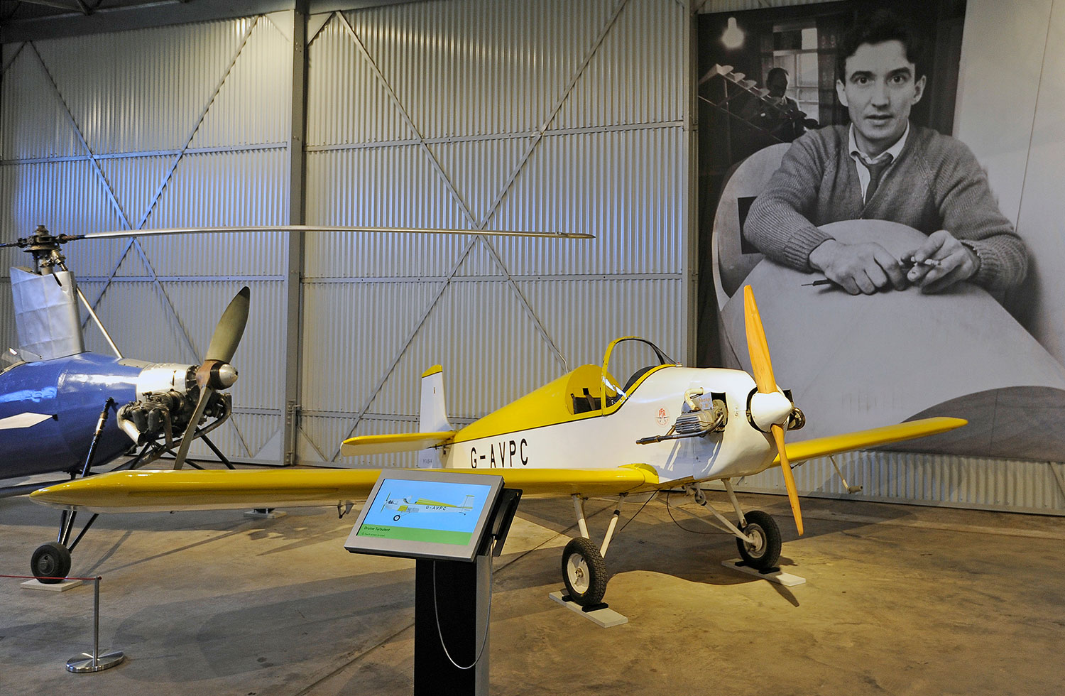 Druine Turbulent aircraft built by John Sharp, with a photo of Sharp behind it.