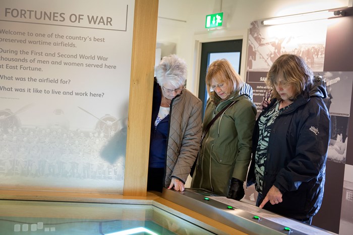 Three women exploring an interactive map in the Fortunes of War gallery,
