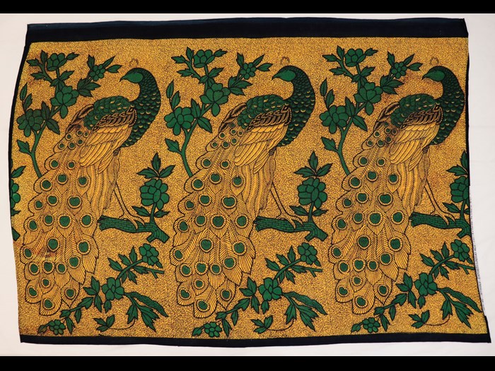 Capulana featuring a repeating pattern of large green and blue stylised peacocks on golden yellow ground: Africa, Southern Africa, Mozambique, 1994-2000.