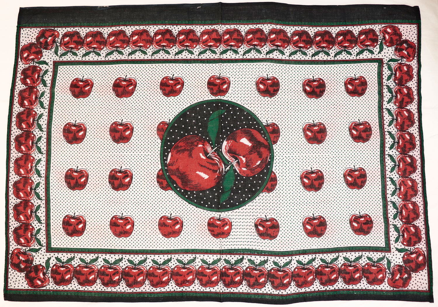 Capulana featuring a pattern of red apple motifs on a spotted white ground with a large central circular motif, enclosed in a rectangular border: Africa, Southern Africa, Mozambique, 1994-2000.