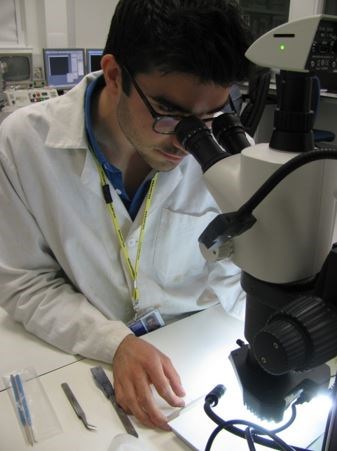 Student intern Jerome Castel looking down a microscope at a sample.