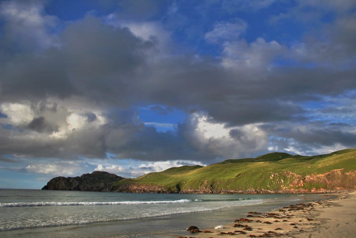 The beach at Uig, with the sea rolling in and hills in the background