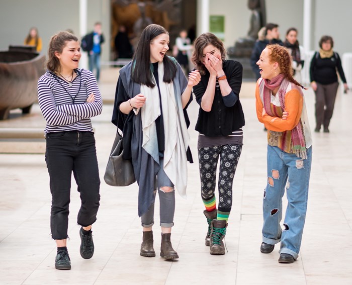 Four teenage girls walking together in the National Museum Scotland.