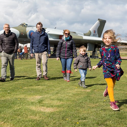 A family of six walking across a grassy field away from a large aircraft