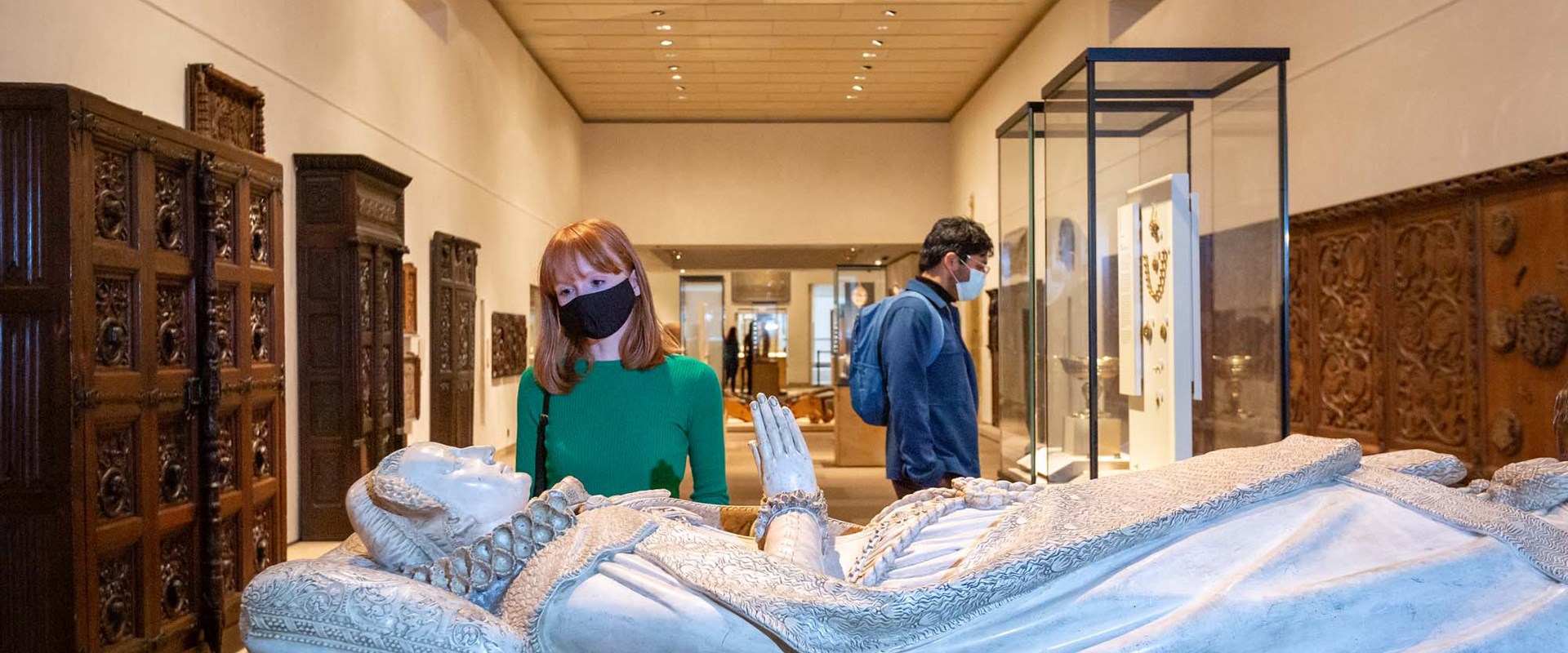 A visitor wearing a mask looks at the replica of Mary Queen of Scots' tomb - a carving of Mary Queen of Scots lying on her back with hands folded in prayer.