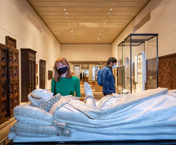A visitor wearing a mask looks at the replica of Mary Queen of Scots' tomb - a carving of Mary Queen of Scots lying on her back with hands folded in prayer.