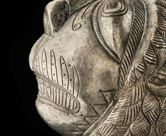 Side view of a face carved on the top of a silver club.