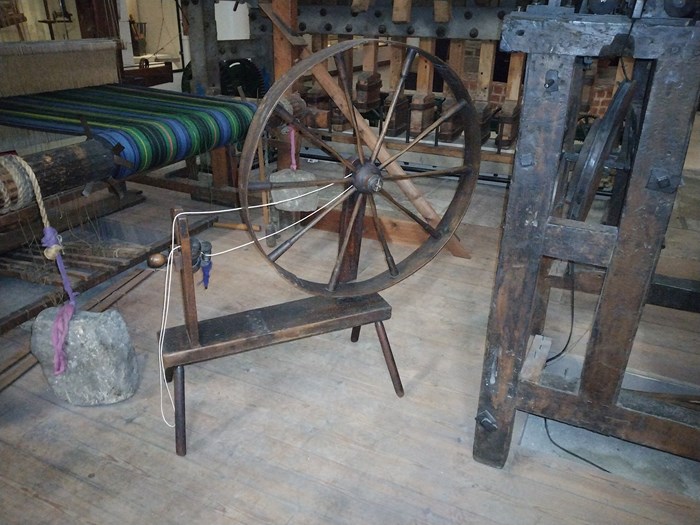 A wooden spinning wheel in a workshop.