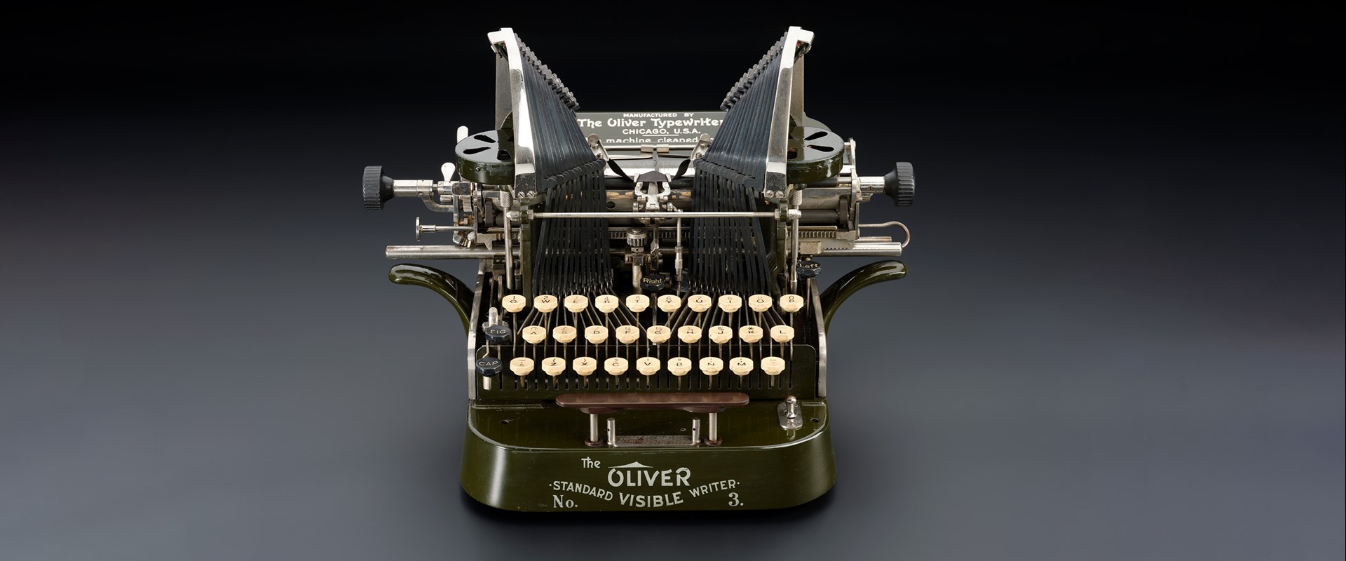 Green mechanical typewriter from the early 1900s with white keys. It says 'The Oliver No. 3, Standard Visible Writer' on the front.