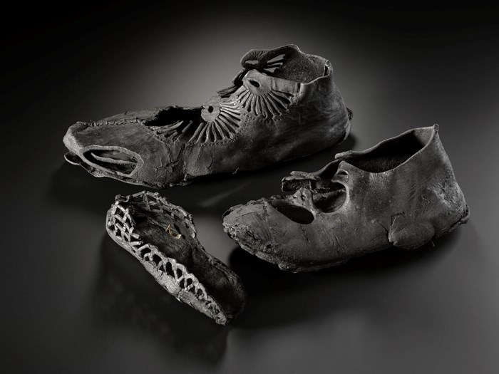 Remains of three leather shoes, two with radial decorative details and straps still intact