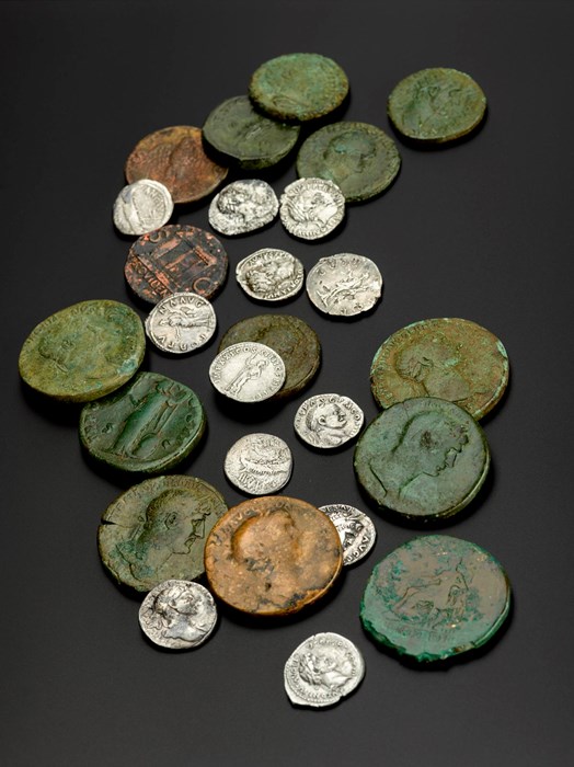 26 coins with faces on them of varying sizes and colours, from small and silver to large and rusted green