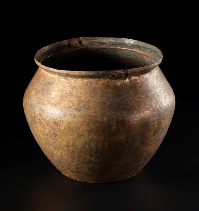 Light brown cooking pot with no lid, tapered at the top and bottom with a sharply protruding bump two thirds of the way up
