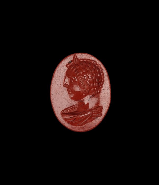 Small, smooth red gemstone, egg-shaped with a profile bust of the emperor sporting curly hair, large nose and a scarf-like wrapping