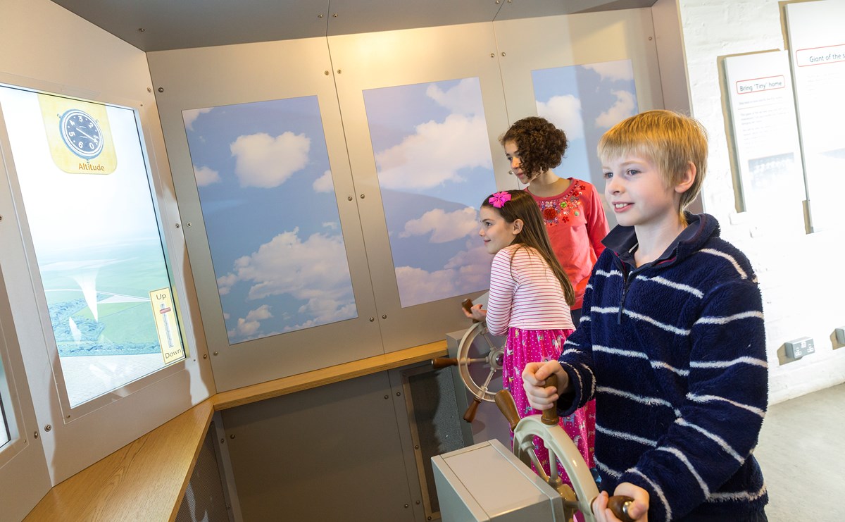 Three children interacting with a display at the National Museum of Flight