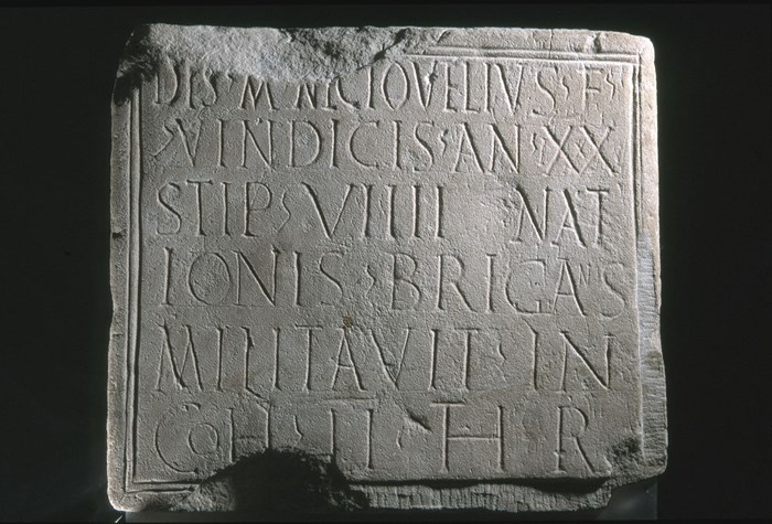 A grey stone slab with six lines of Latin script.