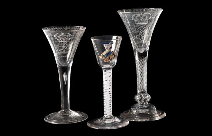 Three decorated wine glasses. The glasses on the left and right have royal crests. The middle glass features a painted portrait of Bonnie Prince Charlie.