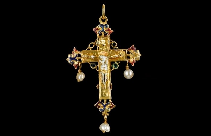 Ornate golden crucifix with blue and red flourishes at the tips. Three pearls hang from it, and Christ on the cross is in the centre.