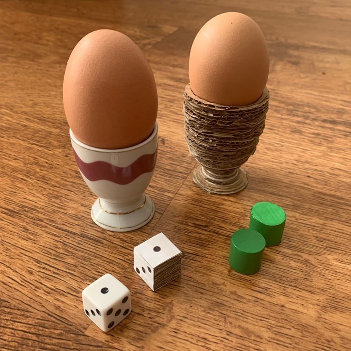 two eggs in egg cups, two dice, and two counters