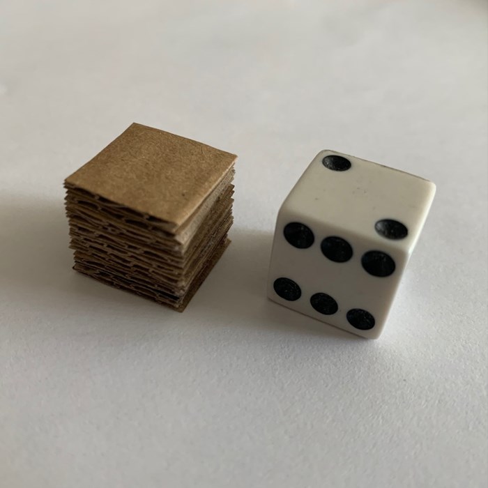 A dice beside a cardboard template
