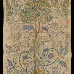 Colour photo of an embroidered wall hanging with foliage, flowers and birds.