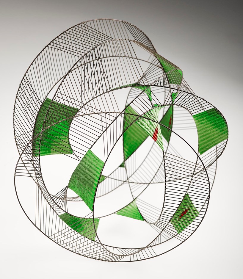 A stainless steel structure with several wires and green tapestry inserts.
