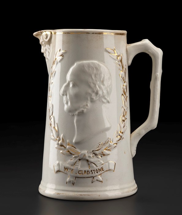 Tall white jug with spout on left and handle on right. Decorated with bust of a man with 'chin strap' facial hair facing left.