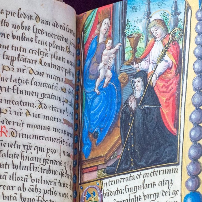 Closeup of an illustration flanked by Latin script. A woman in black with a sceptre kneels before a Saint who holds a baby aloft.