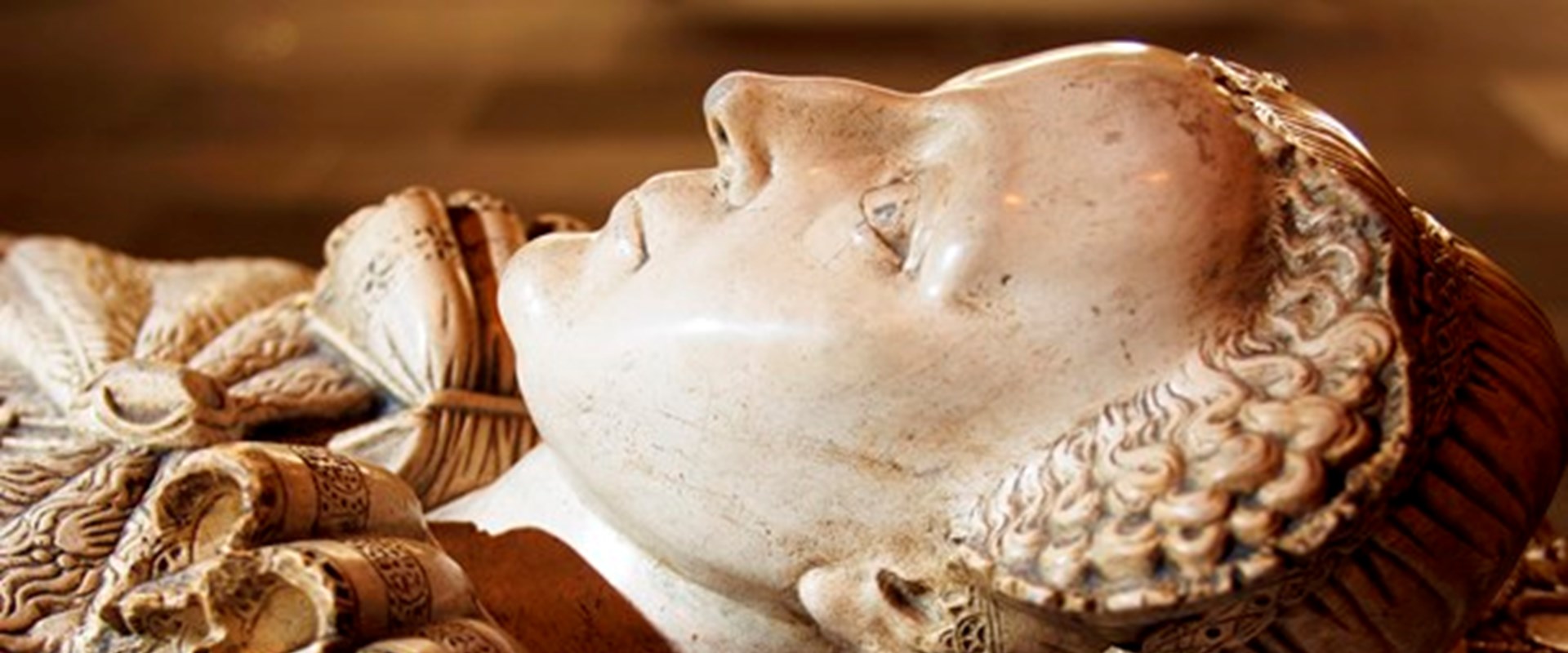 Closeup of a white stone tomb carved to depict Mary, Queen of Scots lying down in full dress.