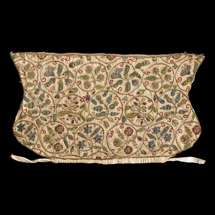 Textile coif, roughly rectangular. Soft yellow base with green vines and red flowers densely patterned across.
