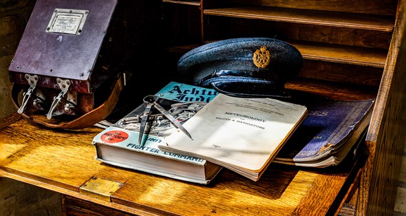 Pilot's books and an RAF cap on a wooden desk.
