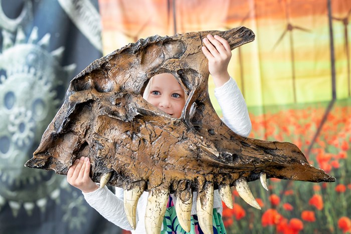 A child holding a portion of a dinosaur skull 