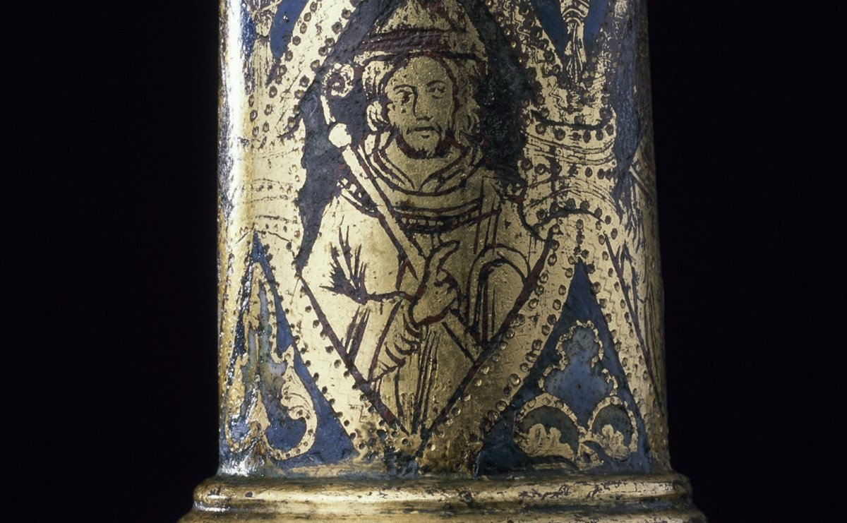 Closeup of detail on the grey-blue crozier staff, revealing a golden saint in a hood holding a crozier within a golden frame.