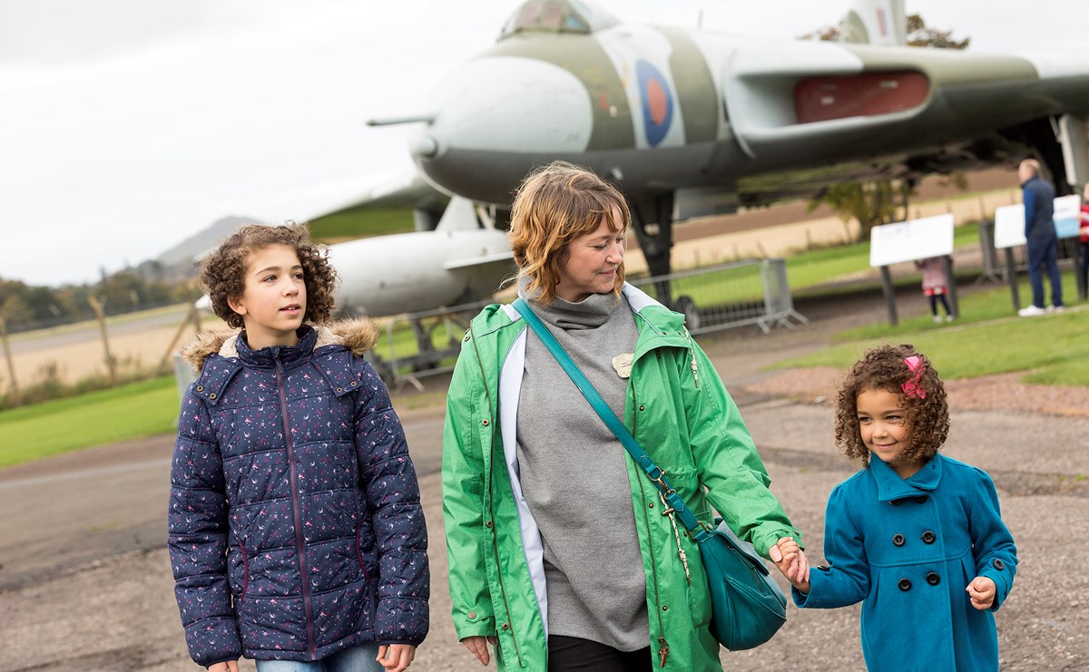 A family walks outside in front of a plane at the National Museum of Flight