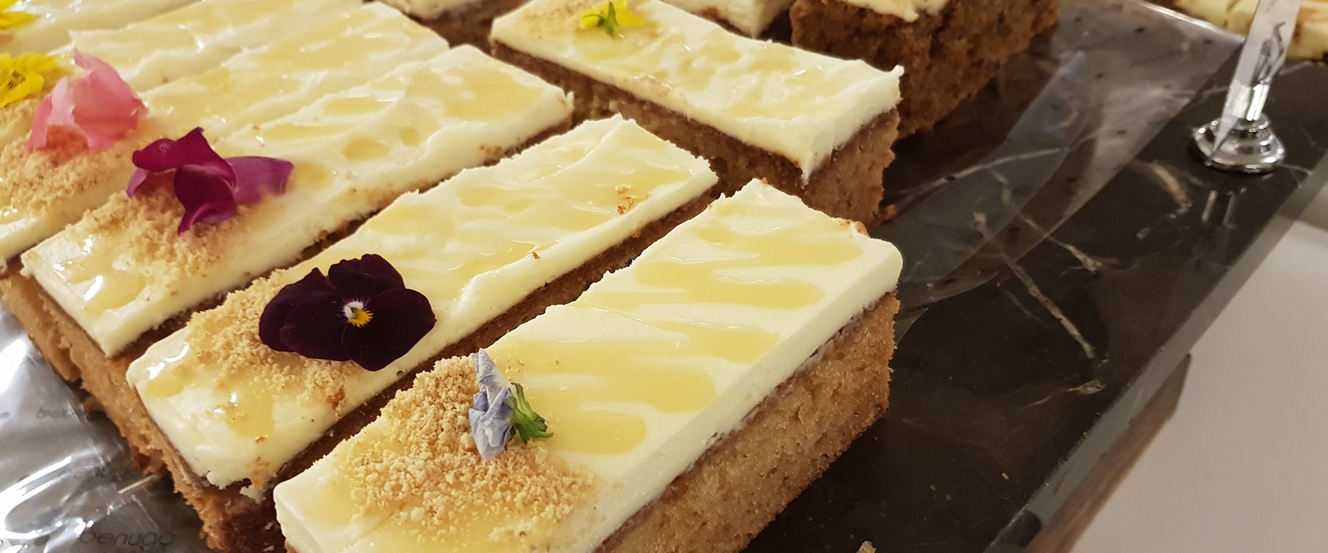Rectangles of yellow cake with white icing and floral decorations