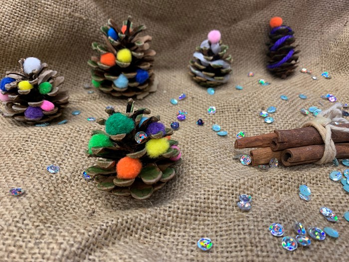 Pinecones decorated with coloured pompoms and sequins.